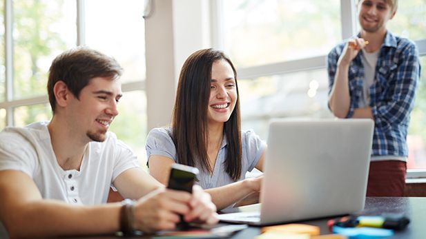 3 students gathered around a laptop 